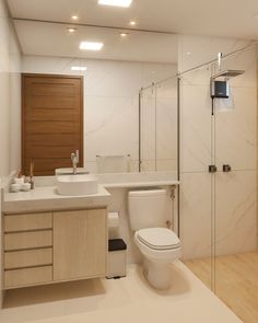 a white toilet sitting next to a sink in a bathroom under a mirror and lights