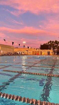 an empty swimming pool with no people in it at sunset or sunrise, and several kites flying overhead