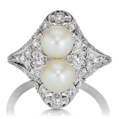 an antique style ring with two pearls and diamonds on the sides, set in white gold