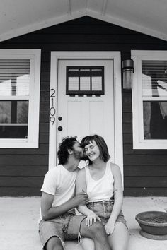 a man and woman sitting in front of a house