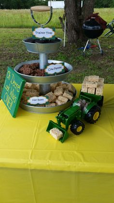 a table topped with three tiered trays filled with treats and desserts next to a tractor