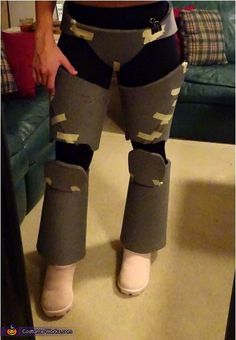 the legs and leg pads of a person in grey pants with white socks, wearing knee pads