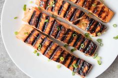 grilled salmon on a white plate with green onions and scallion garnish