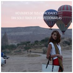 a woman holding a white bag in front of two hot air balloons