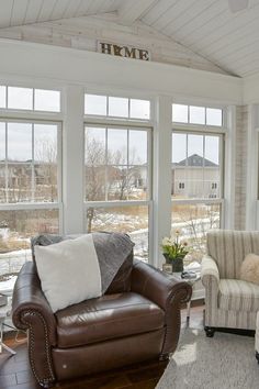 a living room with two couches and chairs in front of large windows that look out onto the yard