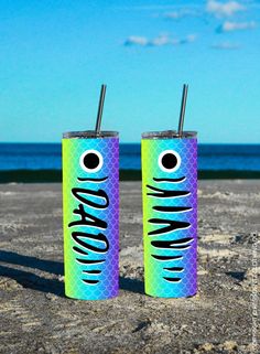 two soda cans sitting on top of a sandy beach