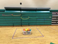 a basket filled with oranges on top of a hard wood floor in a gym