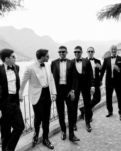 a group of men in tuxedos standing next to each other near the water