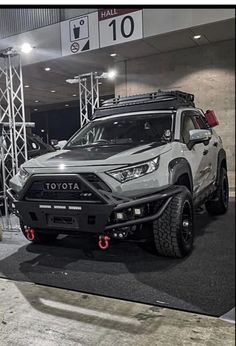 the front end of a white truck parked in a showroom with other vehicles behind it