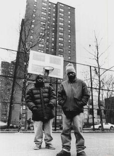 two men standing next to each other in front of a basketball hoop on the street