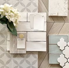 some white and grey tile with flowers on top of it next to two different sized tiles