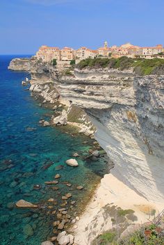 the beach is clear and blue with white cliffs on both sides, along with houses in the background