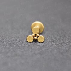 two gold studs sitting on top of a gray surface