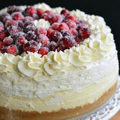 a cake with white frosting and raspberries on top sitting on a plate