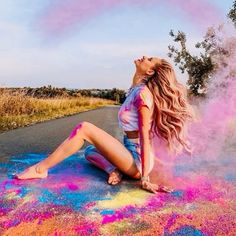 a woman is sitting on the ground with colored powder all over her body and feet