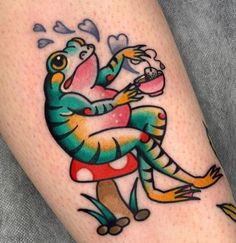 a colorful tattoo on the leg of a person with a dragon holding a heart shaped object