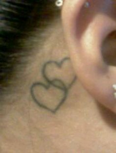 a close up of a person's ear with a heart tattoo on it