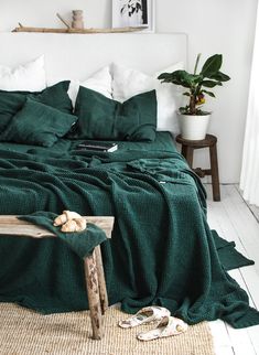 a bed covered in green blankets and pillows