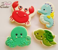 four decorated cookies sitting on top of a white table next to an orange, green and blue sea creature