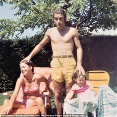 an old photo of a man standing next to two women and a child on a lawn chair