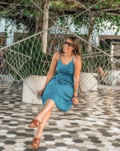 a woman sitting on a hammock in the middle of a tiled floored area