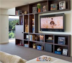 a living room filled with lots of furniture and a flat screen tv mounted on the wall