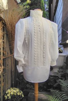 A truly beautiful replica of a Lady,s Heritage Shirt Waist [Blouse] and handmade in your exact measurements. Gently crafted in a cotton-poly batiste,with 100% Cotton Imported Cluny Lace,charming pin tucks and self covered fabric front buttons and full back button closure.Extra long for "tuckability"for the active woman. Custom sizing from S-2XL Paired with a long skirt to celebrate the beauty of eras past. Fitted Cotton Tops With Bishop Sleeves, Fitted Cotton Top With Bishop Sleeves, Classic Tops With Bishop Sleeves For Daywear, Classic Bishop Sleeve Tops For Daywear, White Bishop Sleeve Formal Tops, White Fitted Bishop Sleeve Tops, White Fitted Top With Bishop Sleeves, White Cotton Blouse With Bishop Sleeves, Classic Fitted Blouse With Bishop Sleeves