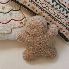 a brown teddy bear laying on top of a pillow next to a christmas tree ornament