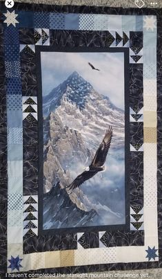 an eagle flying in the sky over a mountain with stars on it's side