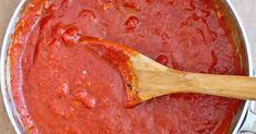 a wooden spoon in a pot full of red sauce