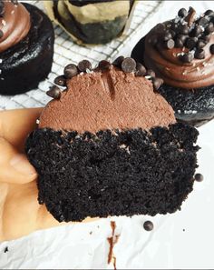 a hand holding a half eaten chocolate cupcake