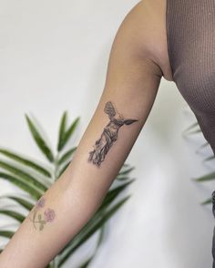 a woman's arm with a tattoo on it and a plant in the background