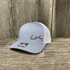 Description These are some cool hats new to the site. Inspired by another comment from a show recently. This stylized Elk Antler is perfect for the hunter or shed hunter in the family. The single horn is low key and this cap is a perfect addition to your hunter's hat collection Key Features Size: One Size Fits Most Fit: Adjustable Snapback Richardson 112 mesh back trucker cap with top-grain leather Sasquatch design Cotton-Poly/Nylon-Mesh material with pre-curved visor Nine colors to choose from: Leather Hat, Richardson Hats, Antler Design, Hunting Hat, Country Hats, Chestnut Leather, Hat Patches, Leather Hats, Diy Hat