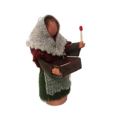 a doll is holding a box with a stick in it's hand and wearing a sweater