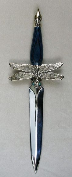 a dragonfly brooch sitting on top of a white table next to a knife