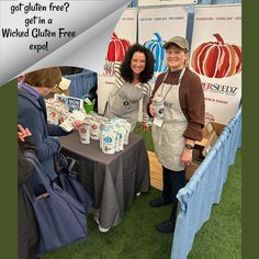 two people standing next to a table with food on it and an advertisement for gluen free expo