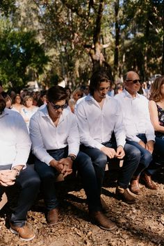 a group of men sitting next to each other on top of a tree covered field