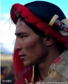 a man with red hair wearing a black hat and braids on his head is looking to the side