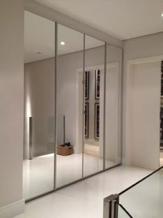 an empty room with glass walls and sliding doors on the side, leading to a bookshelf