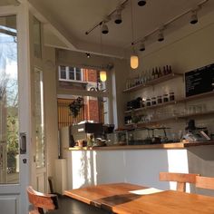 the inside of a coffee shop with wooden tables and chairs in front of an open door