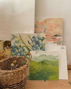 several paintings are on the floor next to a basket