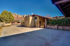 an empty driveway in front of a house with mountains in the background