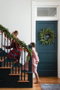 two women are walking down the stairs with wreaths on them