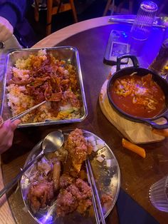 two people sitting at a table with plates of food and bowls of soup in front of them