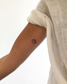 a woman's arm with a small saturn tattoo on the left side of her arm