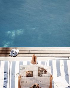 a person laying on top of a deck reading a newspaper