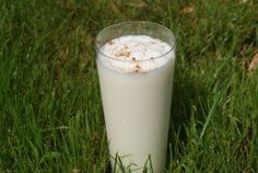 a tall glass filled with milk sitting in the grass