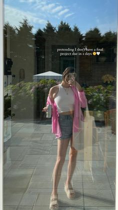 a woman standing in front of a window holding an umbrella and wearing a pink scarf