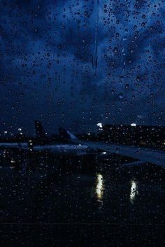 an airplane is parked on the tarmac at night with raindrops all over it