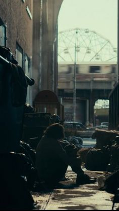 two people sitting on the ground in an alleyway